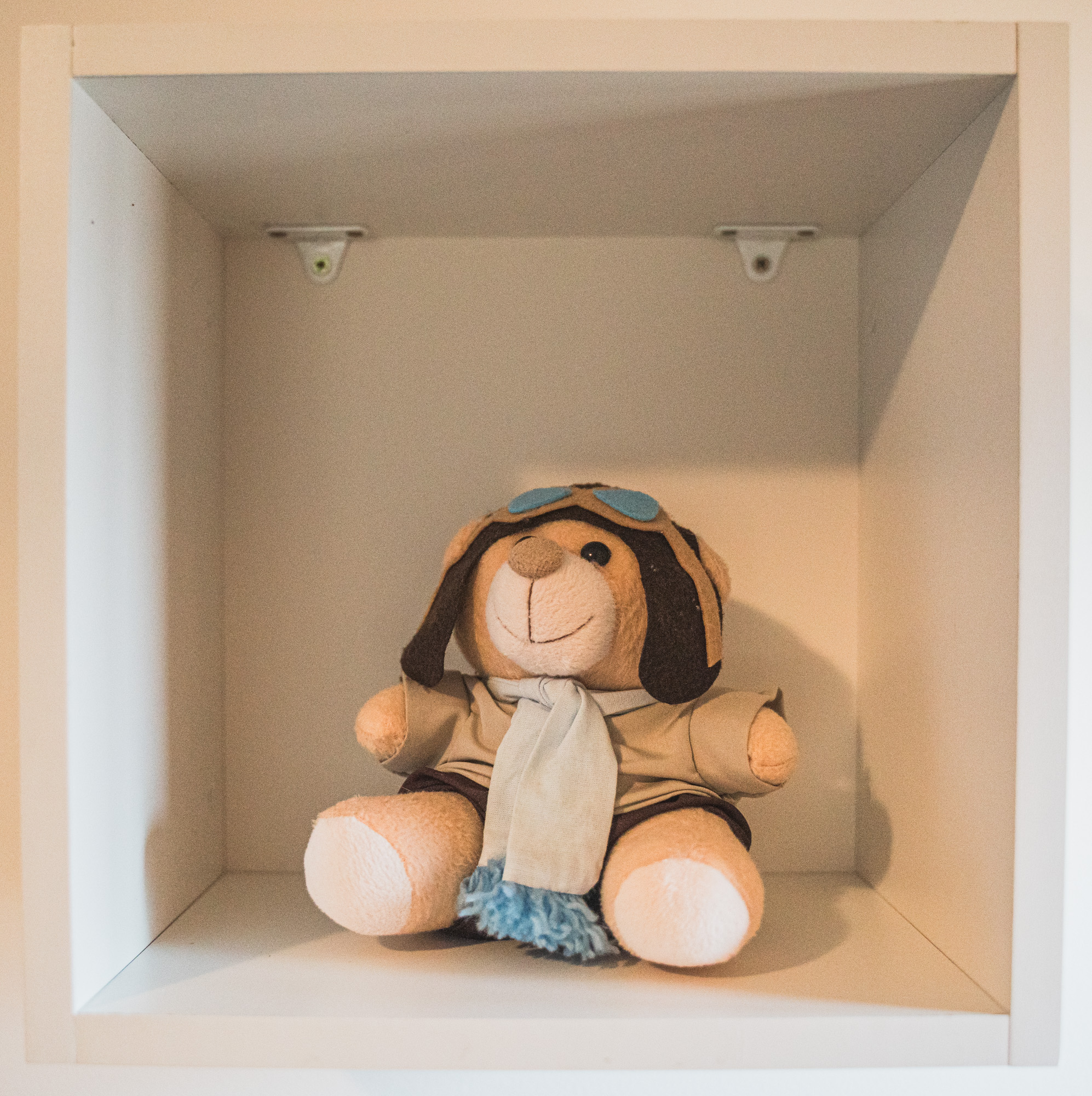 Pequeno aviador de pelúcia em um nicho branco do quarto.